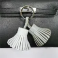 Detail shot of the two-tone leather tassel bag charm keychain with metal ring accessory. - White and Gray