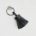 Black leather tassel keychain detail, mini fringe bag charm with metal ring, fine stitching. - Black
