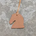 Gros plan détaillé du mini charm de sac tête de cheval en cuir avec texture fine. - Marron