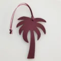 Detailed view of a stylish burgundy palm tree leather bag charm pendant with pink strap. - Burgundy