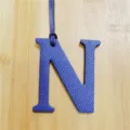 Close-up detail of the blue leather letter N bag charm pendant, showing fine texture and leather cord. - Sapphire Blue