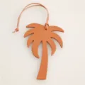 Detailed shot of orange leather palm tree bag charm, fine texture, delicate hanging strap. - Orange