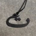 Close-up detail view of the black textured leather Arabic letter pendant bag charm accessory. - Black