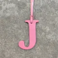 Detail shot of pink leather letter J charm with strap, perfect for bag or car decor. - Pink