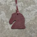 Vue détaillée du charm de sac tête de cheval en cuir texturé, fabrication artisanale raffinée. - Bordeaux