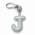 Close-up detail of grey leather letter J bag charm with stitching and leather strap loop. - Gray