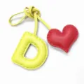 Handmade leather letter D and red heart bag charm, showing exquisite stitching details. - Light Yellow with Bright Red Heart