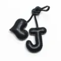 Primo piano dettagliato di un ciondolo per borsa in pelle nera a forma di lettera J e cuore. - Nero con nero