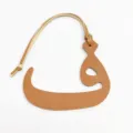 Detalle del colgante de bolso con letra árabe en cuero texturado y correa para colgar. - Marrón