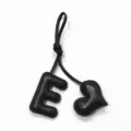 Handmade black leather letter E and heart bag charm detail shot showcasing stitching texture. - Black with Black Heart