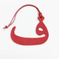 Vista detallada de colgante de bolso de cuero rojo con letra árabe, elegante accesorio. - Rojo