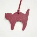 Close-up detail of the burgundy leather cat bag charm pendant, showing fine texture and strap. - Burgundy