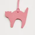 Close-up detail of the pink leather cat bag charm, showing fine texture and strap. - Pink