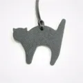 Close-up detail view of the dark grey leather cat bag charm, featuring fine texture. - Black