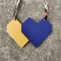 Detailed view of the dual-color geometric leather bag charm with a printed silk ribbon. - Royal Blue and Yellow