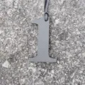 Grey leather number 1 bag charm detail view, minimalist pendant texture close up shot. - Gray