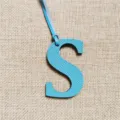 Detailansicht des blauen Leder Buchstaben S Anhängers, stylisches Alphabet Accessoire für Taschen. - Himmelblau