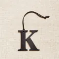 Detail view of the black letter K leather bag pendant, showing its fine texture and cord. - Black