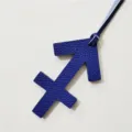 Close-up detail shot of the blue Sagittarius zodiac leather bag charm pendant with fine texture. - Blue