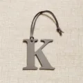 Vue en gros plan détaillée du charm de sac élégant en cuir texturé lettre K grise. - Gris