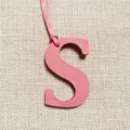 Pink leather letter S bag charm closeup, delicate texture and matching strap for stylish decoration. - Pink