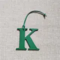 Green leather letter K bag charm detail close-up, showing the fine texture and hanging strap. - Green