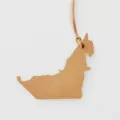 Detailed shot of the leather bag charm featuring textured brown finish and map shape. - Brown