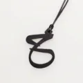 Detailed view of a black textured leather letter pendant with black cord for bag decoration - Black