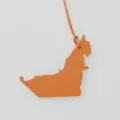 Close-up detail view of the UAE map shaped leather bag charm pendant, elegant texture. - Orange