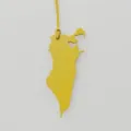 Close up of yellow leather Bahrain map shaped bag charm detail showing texture and fine strap. - Yellow
