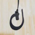 Detailed view of black leather Arabic letter bag charm and car hanging pendant accessory. - Black
