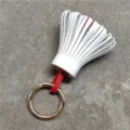 Detailed close-up shot of the white and red leather tassel bag charm with gold ring. - White and Red