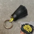 Nahaufnahme des zweifarbigen Leder-Quasten-Anhängers mit geschichteter Struktur und Ring. - Ca. 6x3cm / Innen Hellgelb und Außen Schwarz mit Ring