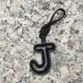 Close-up of black leather letter J bag charm showing neat edge stitching and texture. - Uppercase Letter J / Black