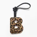 Leopard print leather letter B bag charm detail, premium suede texture with black strap accessory. - Letter B