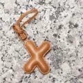 Close-up detail of the light brown leather letter X charm, showing fine stitching and texture. - Letter X / Tan