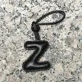 Close-up detail of the black leather letter Z bag charm pendant showing fine stitching texture on stone. - Uppercase Letter Z / Black