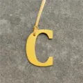 Yellow leather letter C bag charm detail showcasing fine leather texture and hanging strap. - Yellow