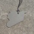 Leather map pendant keychain detail view showing textured grey surface and hanging cord. - Gray