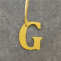Yellow leather letter G handbag charm close-up, stylish initial pendant accessory. - Yellow