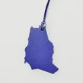 Detailed view of the blue leather map shaped bag charm, showing fine texture and strap. - Blue