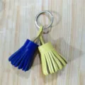 Detailed close-up of dual-color leather tassel keychain fringe ornament for bag and keys. - Blue and Yellow