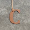 Leather letter C bag charm detail shot, textured brown leather pendant accessory display. - Brown