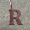 Leather letter R bag charm detail shot, stylish initial handbag pendant with hanging strap. - Burgundy