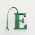 Green leather letter E bag charm detail shot, stylish alphabet pendant accessory for handbags. - Green
