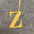 Detailed closeup of the yellow leather letter Z bag charm, premium texture accessory. - Yellow