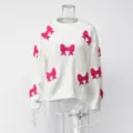 Wit gebreid tricotdetail met roze strikken en zachte textuur op de mouwen. - S / Wit