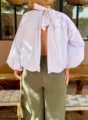Detail shot of the backless white blouse with a stylish bow tie and elegant bubble sleeves. - One Size / White