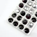 Close up of faceted round pointed back crystal glass rhinestones in a white tray grid. - 6mm 84pcs/pack / Violet