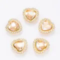 Détail de boutons strass en forme de cœur, cadre doré avec cristal champagne et diamants clairs. - Ombre Dorée